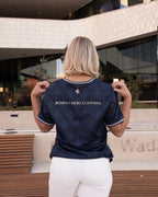 Person wearing a navy blue Bosnian soccer jersey styled with white jeans, standing in front of a modern building.